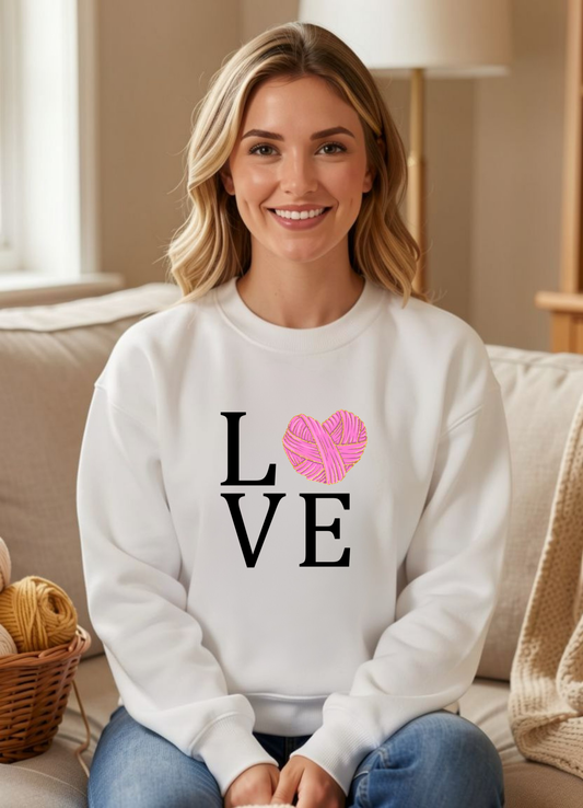 woman wearing white sweatshirt with design reading love with a yarn heart for the o
